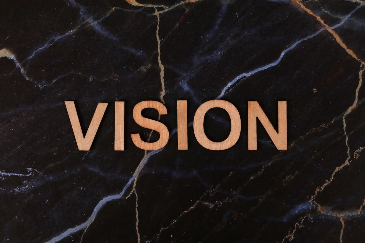 Wooden letters spelling 'Vision' on a dark marble surface, symbolizing clarity and goals.